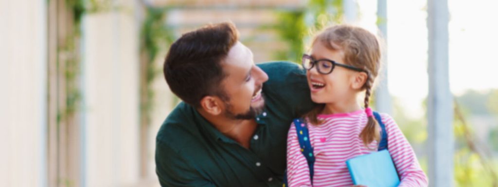 Back to school image of a father with his young daughter, looking at each other and smiling