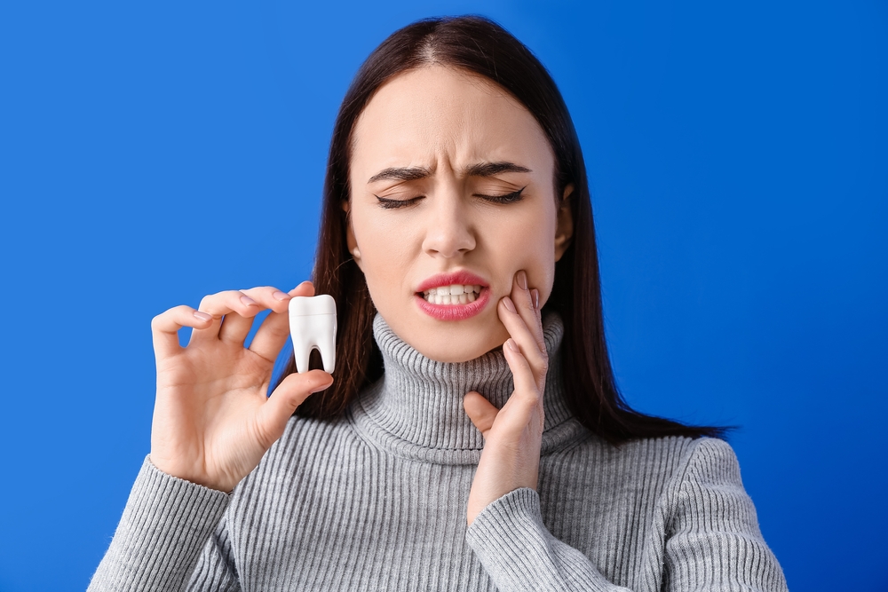 Young woman suffering from tooth ache on color background